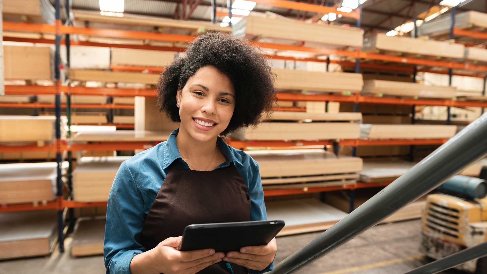 Eine Frau steht mit Tablet in der Hand im Lager