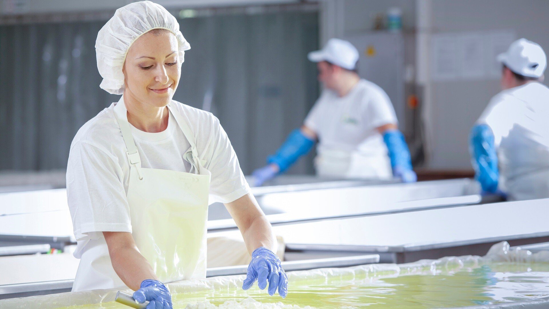 Arbeiterin am Fließband zur Herstellung von weißem Feta-Käse in einer industriellen Fabrik